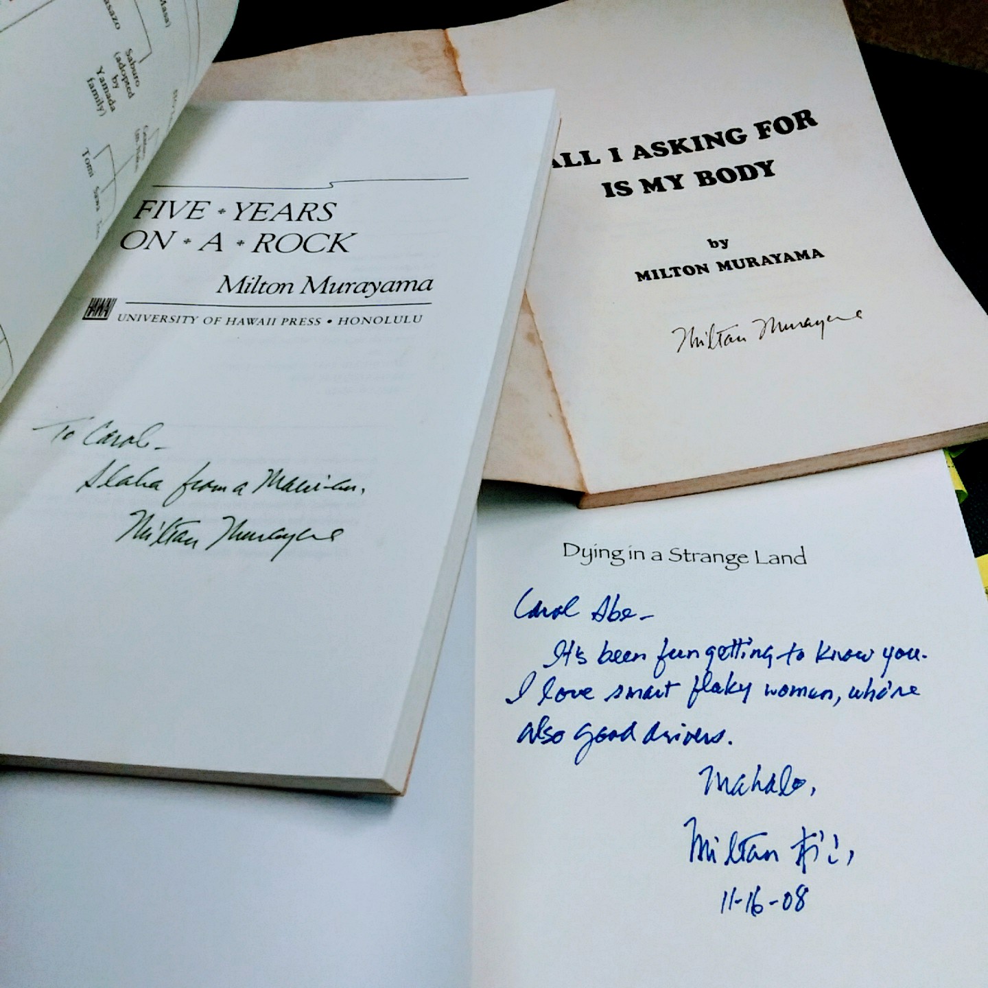 3 books opened to page showing author signed the book