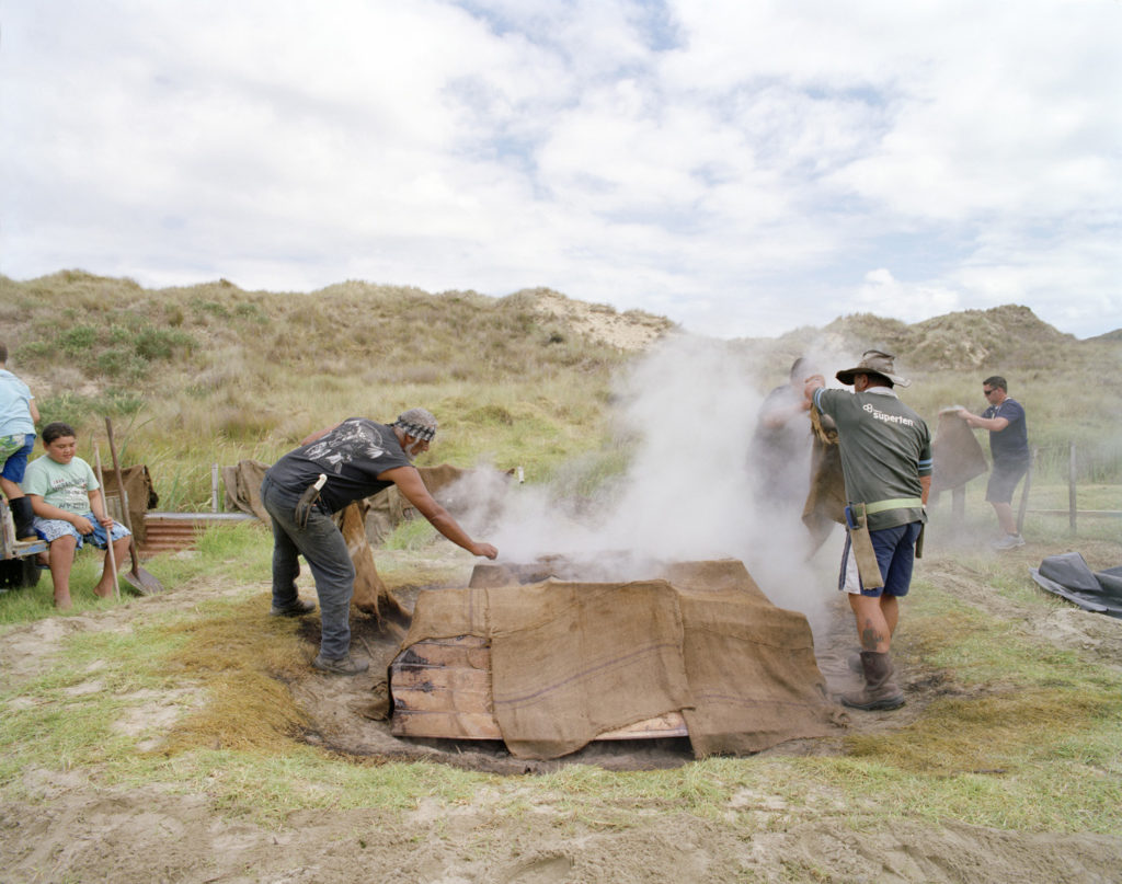 Featured art, this issue: Opening the hangi. Te Wake unveiling. Matihetihe Marae. During the tangihanga for Ralph Hotere, by Natalie Robertson, 2013. Presented as part of a collection titled The Headlands Await Your Coming, this image evokes the practices of ahi kaa roa (keeping the home fires burning) and manaakitanga (offering hospitality to visitors) through the provision of food—practices that proclaim and sustain mana whenua, or intergenerational authority, pride, and tribal connections to land. 